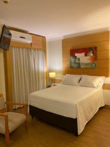 a bedroom with a large bed and a chair at Hotel Aeroporto de Congonhas - Flat in São Paulo