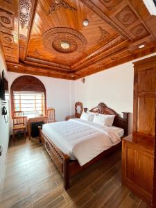 Hotel Hoàng My في بلاي كو: غرفة نوم بسرير كبير بسقف خشبي