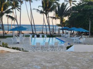 una piscina con sedie e ombrelloni sulla spiaggia di 3 bedroom, front of the beach and pool a Juan Dolio