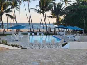 uma piscina com cadeiras e guarda-sóis na praia em 3 bedroom, front of the beach and pool em Juan Dolio