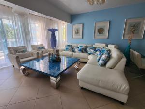 3 bedroom, front of the beach and pool في خوان دوليو: غرفة معيشة مع كنب وطاولة واريكة