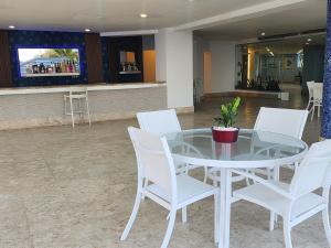 - une table en verre et des chaises blanches dans le hall dans l'établissement 3 bedroom, front of the beach and pool, à Juan Dolio