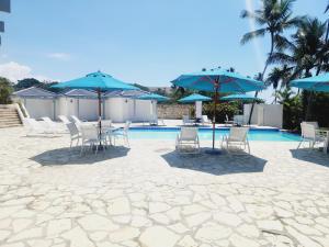 um pátio com cadeiras e guarda-sóis ao lado de uma piscina em 3 bedroom, front of the beach and pool em Juan Dolio