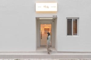 a person standing in the doorway of a white building at Aank Hotel Cheonan Station 1st in Cheonan