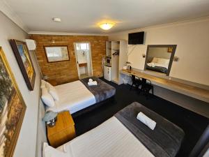 a hotel room with two beds and a desk at Hunter Valley Motel in Cessnock