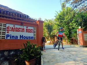 a man riding a bike in front of a pinima house at Pina House in Kep