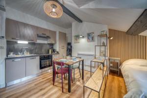 a kitchen and a bedroom with a table and a bed at Le Strasbourg - Centre ville - Climatisation in Grenoble +12 photos