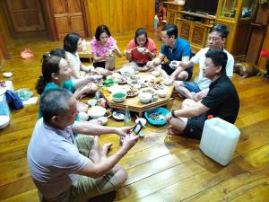 un grupo de personas sentadas alrededor de una mesa comiendo en Nặm Pé Homestay, en Bak Kan