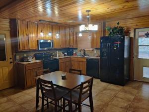 a kitchen with a table and a black refrigerator at Quiet cabin near Enid Lake in Enid