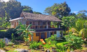 a house with a balcony in the middle of a yard at Villa c'est la vie in Nosy Komba