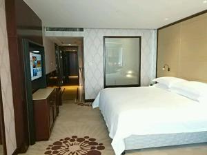 een slaapkamer met een groot wit bed en een televisie bij Hengna International Hotel in Yiwu