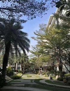 a park with palm trees in front of a building at Elements Srinakarin in Ban Khlong Prawet