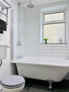 a white bathroom with a tub and a toilet at Lovely Westbourne apartment - 15 min walk to beach in Bournemouth