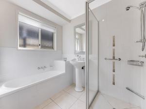 a white bathroom with a sink and a shower at 11 Wills Avenue Golden Beach QLD in Golden Beach +5 photos