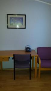 un tavolo con sedia viola e una scrivania con telefono di Tana Vertshus a Bånjakas Altre 3 foto