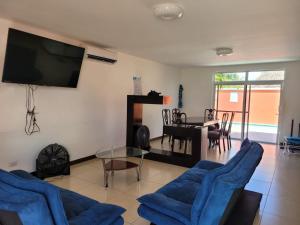 a living room with blue chairs and a tv at Casa en condominio monterrico in Iztapa
