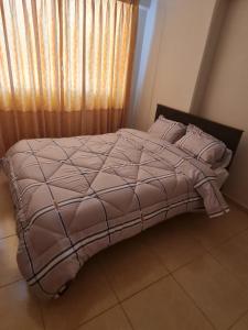 1 cama con edredón marrón y almohadas en un dormitorio en Departamento céntrico Huancayo, en Huancayo