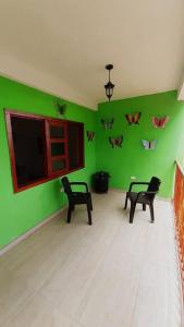 Zimmer mit grünen Wänden, 2 Stühlen und einem TV in der Unterkunft EcoCasa Romantica vista a Cali disfruta en pareja o familia in Yumbo