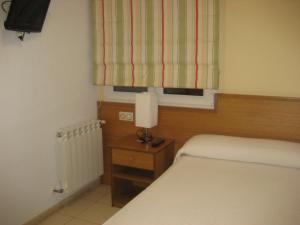 1 dormitorio con cama, lámpara y ventana en Pensión Residencia Caola, en Arteixo