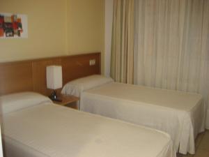 una habitación de hotel con 2 camas y una lámpara en Pensión Residencia Caola, en Arteixo