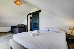 1 dormitorio con 1 cama blanca grande y 1 silla en Manzel D Ziles - Piscine chauffée, en Saint-Pierre