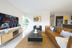 sala de estar con sofá y TV en Wyndham 5BR Spacious Holiday Vacation Home WiFi, en Truganina