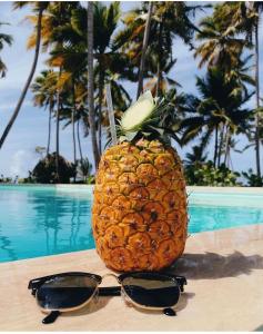 a pineapple with sunglasses on a table near a pool at Villa Brise de Mer in Las Terrenas