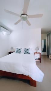 1 dormitorio con 1 cama blanca y ventilador de techo en Villa Brise de Mer, en Las Terrenas