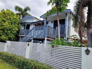 a house with a white fence and palm trees at Homestay at Julie's in Cairns
