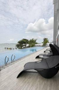 a resort with a pool and chairs next to the water at One Residence Apartment 2BR near Ferry Terminal in Batam Center