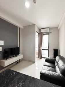 a living room with a couch and a flat screen tv at One Residence Apartment 2BR near Ferry Terminal in Batam Center +7 photos