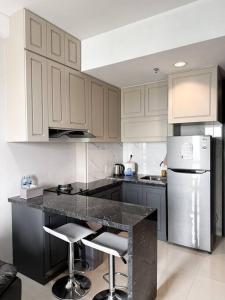 a kitchen with white cabinets and a black counter top at One Residence Apartment 2BR near Ferry Terminal in Batam Center