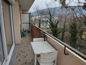 uma varanda com uma mesa branca e cadeiras em Charmant appartement au bord du Thiou - Annecy em Annecy