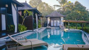 a swimming pool with chairs and a house at Kayangan Villa Ubud in Tegalalang