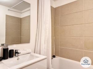 La salle de bains est pourvue d'un lavabo blanc et d'une douche. dans l'établissement Kheyl Home 2 étoiles - T3 de 47 m2 à Saint-Denis, à Saint-Denis