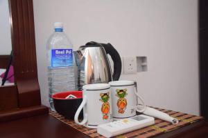 a counter with two coffee mugs and a bottle of water at Serendib Village Guest House in Negombo