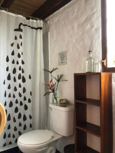 a bathroom with a toilet and a shower curtain at Hostal Los Orishas in Ayampe