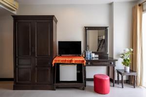 1 dormitorio con escritorio, TV y espejo en Garden Phuket Hotel, en Patong Beach