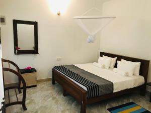 - une chambre avec un lit, un miroir et une chaise dans l'établissement Holly Flowers Villa, à Sigirîya