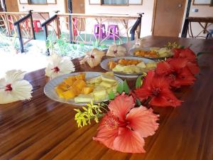 a wooden table topped with plates of fruit and flowers at Moorea Vaiare Lodge in Moorea +18 photos