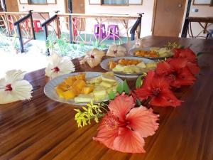 a wooden table topped with plates of fruit and flowers at Moorea Vaiare Lodge in Moorea