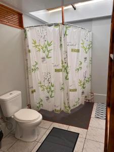 a bathroom with a toilet and a shower curtain with plants at Moorea Vaiare Lodge in Moorea