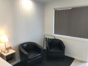 - deux chaises noires dans une chambre avec fenêtre dans l'établissement Room Motel Kingaroy East, à Kingaroy
