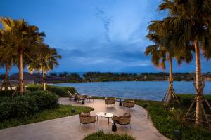 a patio with palm trees and a lake at New World Hoiana Beach Resort in Hoi An