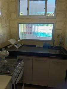 uma cozinha com um lavatório, um fogão e uma janela em Condomínio Wembley Mar III - APT 114 em Ubatuba