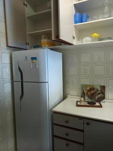 uma cozinha com um frigorífico branco e uma taça de fruta em Condomínio Wembley Mar III - APT 114 em Ubatuba