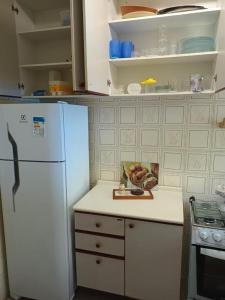 uma cozinha com um frigorífico branco e uma taça de fruta em Condomínio Wembley Mar III - APT 114 em Ubatuba