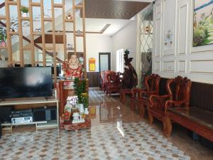 MyTran Homestay-HauLoan في كوي نون: غرفة معيشة مع تلفزيون بشاشة مسطحة وكراسي