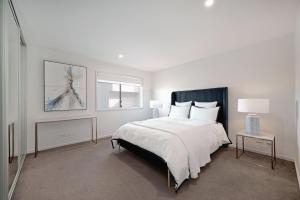ein weißes Schlafzimmer mit einem großen Bett und einem Fenster in der Unterkunft The Menzies Suite in Canberra