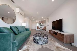 ein Wohnzimmer mit einem grünen Sofa und einem Flachbild-TV in der Unterkunft The Menzies Suite in Canberra